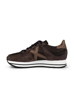 Zapatillas de ante marrón con acentos de malla, cordones negros, entresuela blanca con detalle de rayas negras y diseño de puntera redondeada.