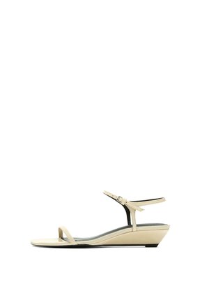 Sandale compensée beige avec une fine bride à l’orteil et une bride à la cheville, talon bas, vue de côté sur fond blanc.