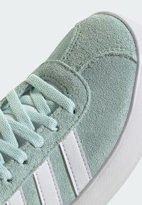 Basket en suede vert menthe avec des rayures blanches en synthétique, surface texturée et lacets assortis, dotée d'une pointe arrondie et d'une semelle en caoutchouc.