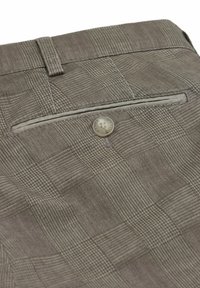 Gros plan sur la poche arrière d'un pantalon à carreaux marron avec un bouton et un passant de ceinture sur un tissu texturé.