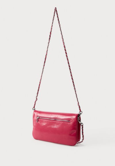 Μικρό γυαλιστερό κόκκινο δερμάτινο τσαντάκι με ασημί φερμουάρ και αλυσίδα πλεγμένη με κόκκινο δέρμα, κρεμασμένο σε ανοιχτό φόντο.