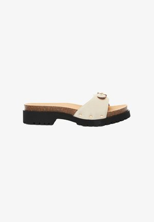 Light beige slide sandal with a textured strap, cork footbed, black rubber outsole, and gold stud accents.