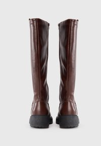 Botas de cuero marrón hasta la rodilla con una textura lisa, que cuentan con suelas de goma negras y un detalle de cremallera lateral para facilitar su uso.