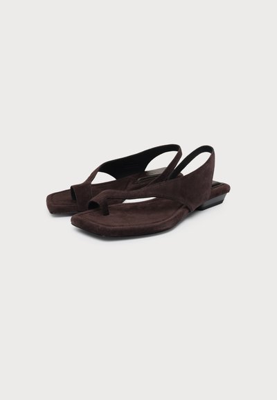 Ζευγάρι καφέ σουέτ slingback σανδάλια με τετράγωνες μύτες και θηλιές δαχτύλου, επίπεδες σόλες, σε λευκό φόντο.