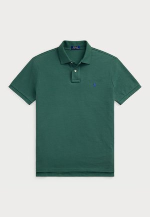 Zielona koszulka polo wykonana z bawełny, z klasycznym kołnierzykiem, dwoma guzikami, krótkimi rękawami oraz niebieskim haftowanym logo po lewej stronie klatki piersiowej.