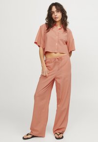 Kurze ärmellose, verkürzte Button-Up-Bluse und weit geschnittene Hose aus leichtem Terrakotta-Stoff, mit einem Kordelzugbund und einer lockeren Passform.