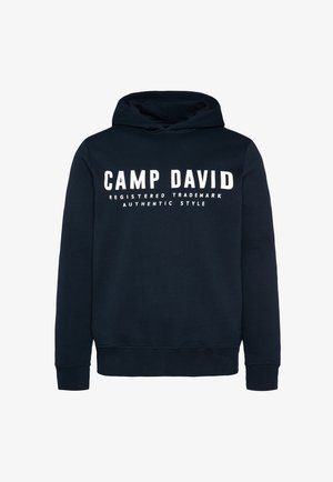 Sudadera azul marino con un bolsillo tipo canguro en la parte delantera, puños y dobladillo de canalé. Presenta texto en blanco: "CAMP DAVID" y "MARCAS REGISTRADAS ESTILO AUTÉNTICO."