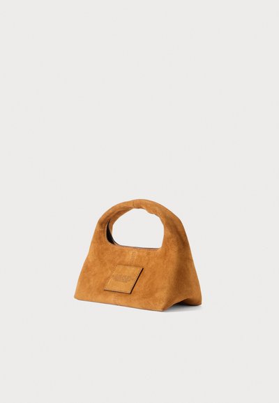 Small brown suede handbag with a soft rounded handle and a rectangular patch on the front, set against a plain white background.