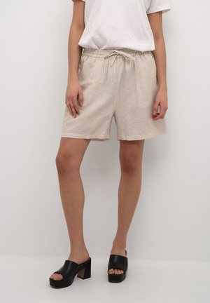 Beige gestreifte Shorts aus leichtem Stoff, mit einem elastischen Bund und Kordelzug. Getragen mit schwarzen Plateausandalen.