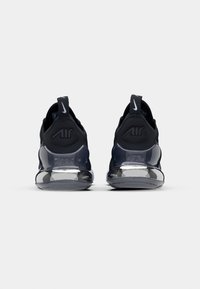 Scarpe da ginnastica nere con un design elegante, dotate di una suola d'aria trasparente e pannelli posteriori texturizzati. Marchio Nike ben visibile sul tallone.