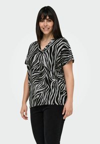 Svart och grå zebramönstrad kortärmad topp med V-ringning, tillverkad i ett lätt tyg, med en avslappnad passform och mjuk textur.