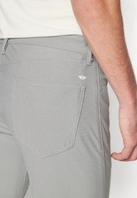 Pantaloni grigi con tessuto testurizzato, dotati di una tasca posteriore, un sottile logo e impunture a contrasto lungo i bordi.