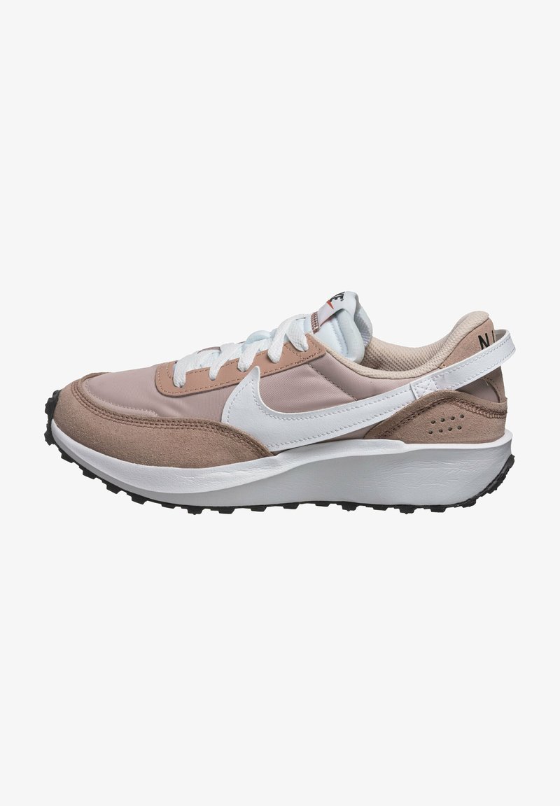 Baskets Nike présentant un mélange de matériaux rose clair et beige, avec un Swoosh blanc, un col rembourré, des lacets blancs et une semelle en caoutchouc noire.