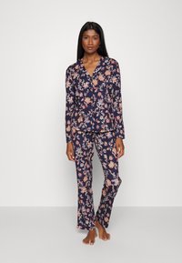 Blommig pyjamas i marinblått med färgglada blommönster. Långärmad knäpptopp och matchande byxor i lättviktsmaterial.