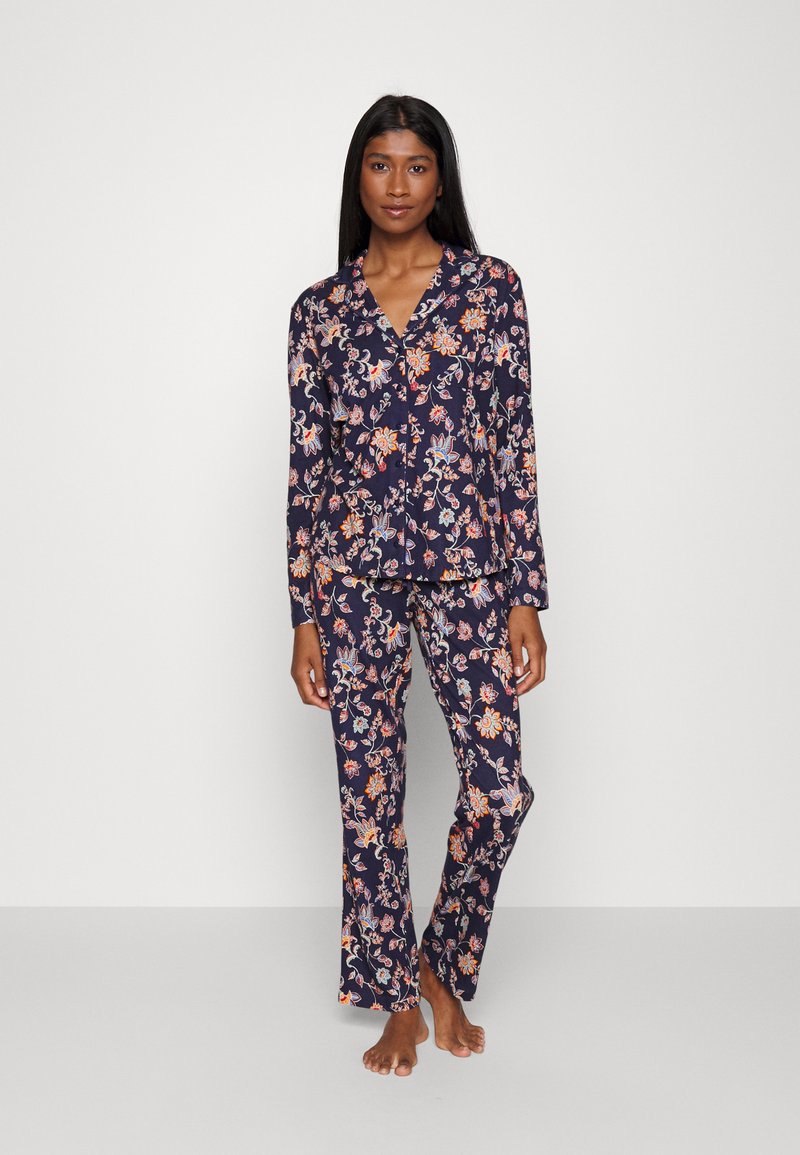 Blommig pyjamas i marinblått med färgglada blommönster. Långärmad knäpptopp och matchande byxor i lättviktsmaterial.