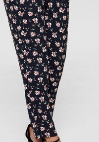 Pantalon à motif floral en tissu bleu marine, avec des fleurs roses et blanches et des accents verts, texture douce et coupe fuselée.