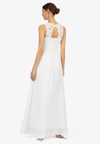 Abito maxi bianco con dettagli in pizzo sulla schiena e corpetto arricciato. Presenta una gonna fluida e un'apertura a chiave sulla schiena.