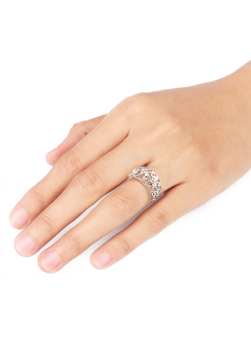 Silberring mit filigranem Design, geschwungene Form, glänzende Oberfläche, getragen an einer Hand mit natürlichen Nägeln vor einem weißen Hintergrund.