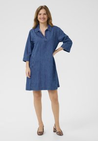 Blauwe spijkerjurk met een kraag, halve mouwen, zijzakken en een relaxed fit, met een rechte zoom. Draag het met geprinte schoenen.