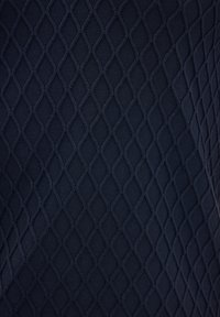 Marinblått textil med ett diamantmönster, strukturerat med upphöjd sömnad. Materialet verkar vara stickat och tätt vävt.