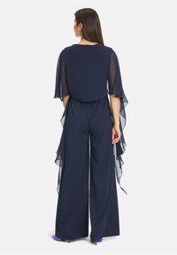Marineblauer Jumpsuit mit durchsichtigen Kapuzenärmeln, weitem Bein und glattem Stoff. Verfügt über einen schlichten runden Ausschnitt und fließende Designelemente.