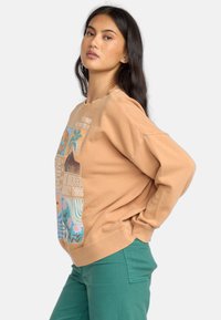 Beige sweatshirt met grafisch ontwerp van palmbomen, bergen en bloemen. Losse pasvorm, ribgebreide manchetten, zachte stof, zijnaaddetails.