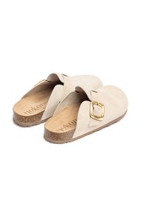 Sabots en suède beige à enfiler avec une large sangle et un détail en boucle dorée, complétés par une semelle en liège et une semelle extérieure en caoutchouc texturé.