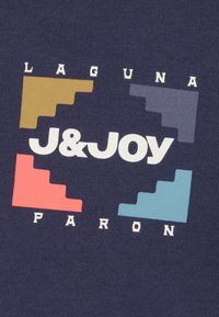 Marineblauwe stof met een centraal wit logo "J&Joy" en de woorden "LAGUNA" en "PARON". Vier gekleurde accentblokken in bruin, rood, grijs en teal.