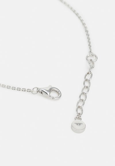 Catena in metallo argento con un gancio e un charm circolare. Presenta una superficie liscia e un piccolo logo sul charm, collegato da anelli.