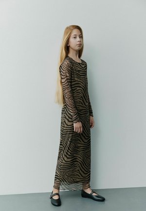 Langes, transparentes Kleid mit einem braun-schwarzen Zebra-Print, ausgestattet mit langen Ärmeln und einem lockeren Schnitt, kombiniert mit flachen schwarzen Schuhen.