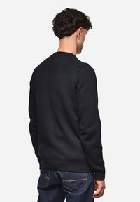 Dunkler Strickpullover mit Rundhalsausschnitt und gerippten Bündchen, mit einer strukturierten Oberfläche, von hinten vor einem schlichten Hintergrund gezeigt.