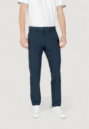 Pantaloni navy realizzati in tessuto leggero, con taglio dritto, passanti per cintura e tasche anteriori, abbinati a sneaker bianche.