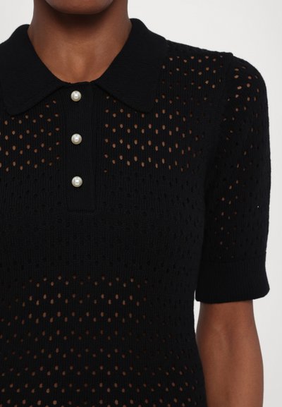 Schwarzes gestricktes Polo-Shirt mit einem strukturierten offenen Muster, kurzen Ärmeln und drei Perlenknöpfen auf der Vorderseite. Mit Kragen und subtiler Ripp-Optik.