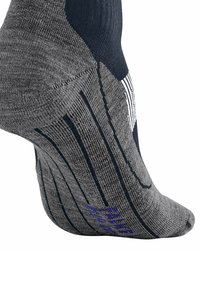Calcetín de rendimiento gris con acentos en azul marino, que presenta rayas texturizadas y un logo morado impreso cerca del dedo del pie. Diseño de talón reforzado.