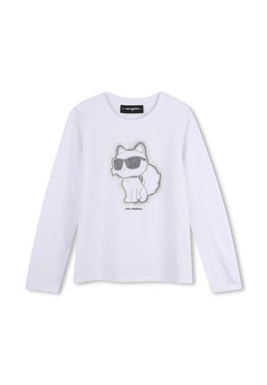 Chemise blanche à manches longues avec un contour en pointillés d’un chat portant des lunettes de soleil et le texte Karl Lagerfeld en dessous du chat.