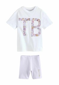 Bijela pamučna majica s ružičastim i �žutim cvjetnim "TB" grafikonom i tekstom "By Ted Baker"; uparena s ljubičastim hlačama koje imaju zlatni tekst "BAKER".