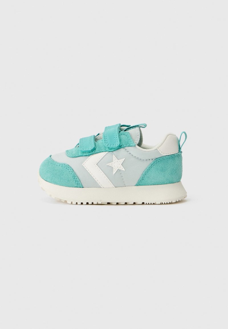 Baskets bleu clair et blanches pour tout-petit avec deux bandes velcro et un logo étoile sur le côté, présentées sur un fond uni gris clair.