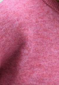 Sweter z dzianiny w miękkiej, strukturalnej tkaninie. Posiada jasnoróżowy odcień z subtelnymi różnicami w kolorze. Okrągły dekolt.