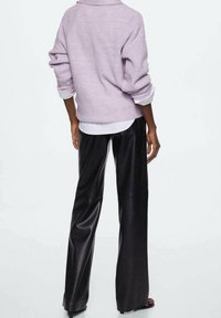 Liliowa dziany sweter z kołnierzykowym dekoltem, zestawiony z czarnymi szerokimi spodniami z ekologicznej skóry; gładka faktura, casualowy krój i warstwowy wygląd.
