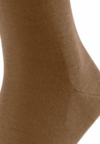 Calzino di cotone marrone con una texture liscia e un fine costine, costruito senza cuciture con una forma aderente per comfort e durata.
