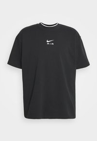 Svart kortärmad t-shirt i bomull. Har en vit Nike-logotyp och texten "AIR" på bröstet. Rund halsringning med kontrasterande vit kant.