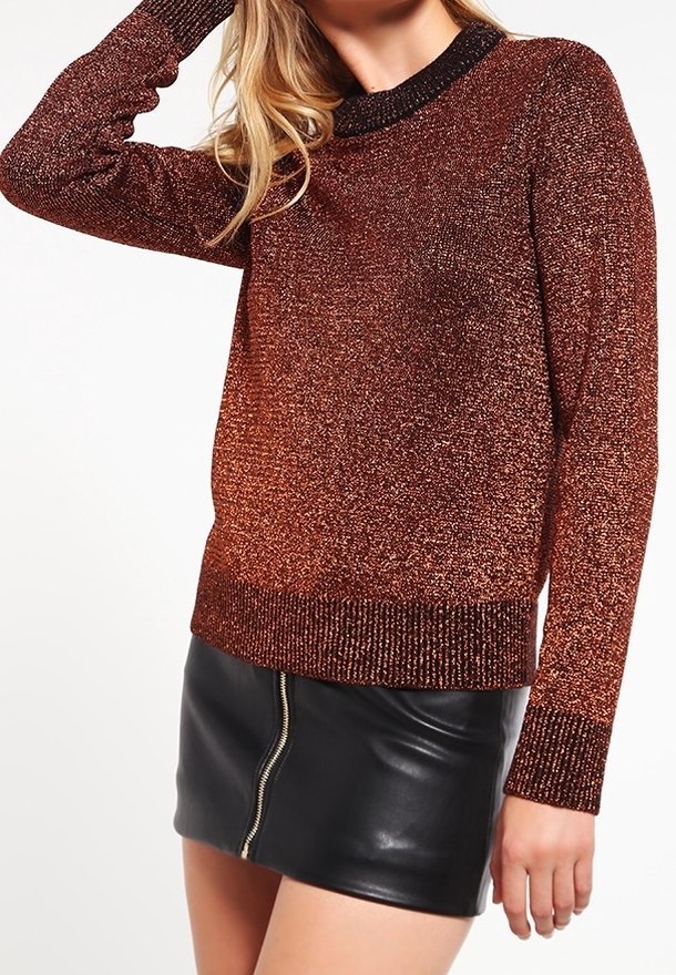 Suéter brillante de color cobre con un cuello y puños negros acanalados, combinado con una mini falda de cuero negra con un cierre frontal.