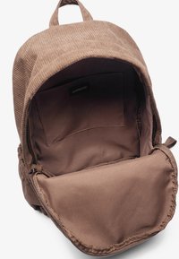 Sac à dos en velours côtelé marron avec une fermeture éclair et un intérieur en tissu doux. Comprend un compartiment principal et une petite poche intérieure.