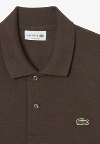 Polo shirt Lacoste marrone con colletto a costine, due bottoni e logo coccodrillo verde sul petto. Vestibilità classica con tessuto testurizzato.