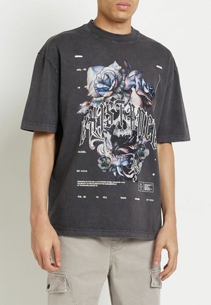 Graphic oversized t-shirt in dark gray cotton, featuring a floral design in blue and purple with bold text and accents on the front.