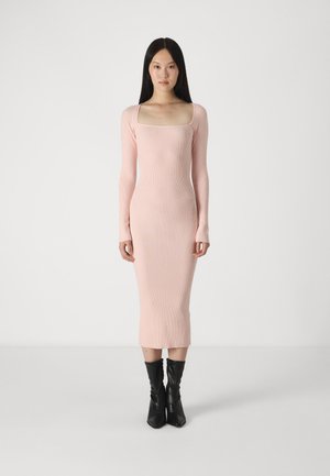 Midi šaty s dlouhými rukávy a ribbed texture v jemné růžové barvě, s hranatým výstřihem. Kombinované s černými, přiléhavými kotníkovými botami.