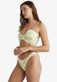 Zeleno-bílý vzorovaný bikiny set obsahující krátký top s tenkými ramínky a vysokými kalhotkami, hladkou texturu a přiléhavý design.