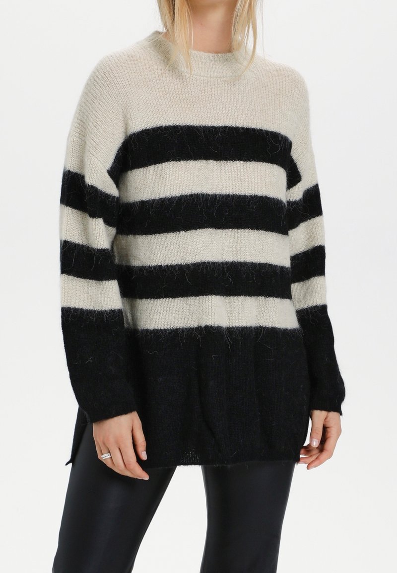 Musta ja kerma-valkoinen raidoitettu neulepaita, jossa on korkea kaulus, pitkät hihat ja rento istuvuus. Valmistettu pehmeästä, teksturoidusta neuleesta.