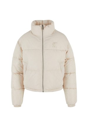 Vycpaná bomber bunda v svetlej béžovej farbe. Má vysoký golier, predný zips a elastické manžety. Diskrétné logo na ľavej hrudi. Hladká textúra.