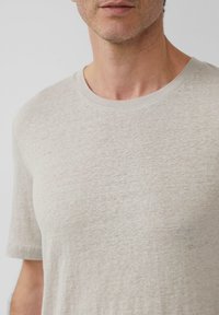 Helles graues Rundhals-T-Shirt aus weichem, strukturiertem Stoff. Es hat kurze Ärmel und minimale Nähte, die einen lässigen, entspannten Schnitt bieten.